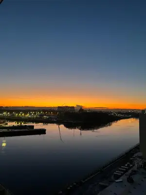 a large body of water with the sunset in the background at Stylish Clyde Riverfront Flat with Balcony Views in Glasgow