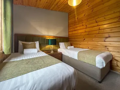 two beds in a room with wooden walls at Lodge 2 - Uk51263 in Glasgow