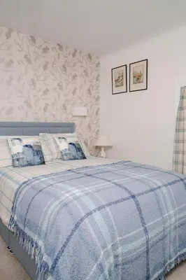 a bedroom with a bed with a blue and white blanket at Fir Tree Lodge - Seasgair Lodges in Crieff