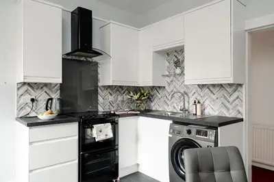a kitchen with white cabinets and a washer and dryer at Fir Tree Lodge - Seasgair Lodges in Crieff