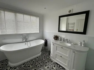 a bathroom with a tub and a sink and a mirror at Mid- Village Croft in Cairndow