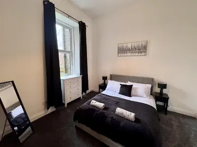 a bedroom with a bed and a large window at Station Road Apartment - Macaulay Letting in Dumbarton