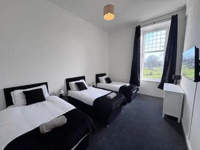 two beds in a room with a window at Station Road Apartment - Macaulay Letting in Dumbarton