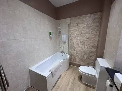 a bathroom with a white tub and a toilet at Station Road Apartment - Macaulay Letting in Dumbarton