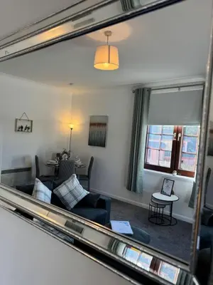 a reflection of a living room in a mirror at Central 1BR Apt with Parking in Auchterarder