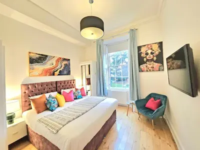a bedroom with a large bed and a blue chair at Stellar Apartments - 2 & 3 Bedroom Apartments in Edinburgh