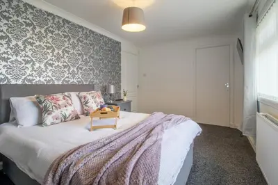 a bedroom with a bed with a table on it at Culzean House - 2 Bedrooms in Coatbridge in Coatbridge