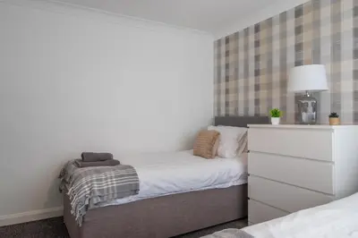 a small bedroom with a bed and a dresser at Culzean House - 2 Bedrooms in Coatbridge in Coatbridge