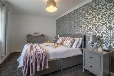 a bedroom with a bed and a wall with wallpaper at Culzean House - 2 Bedrooms in Coatbridge in Coatbridge