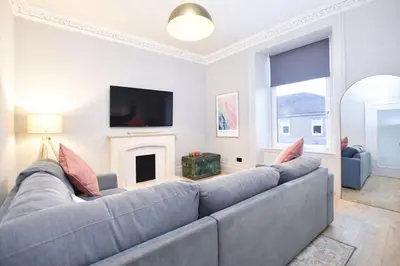 a living room with a gray couch and a fireplace at Portside Apartment in Greenock