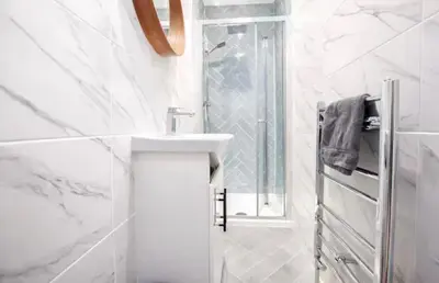 a white bathroom with a sink and a shower at Portside Apartment in Greenock