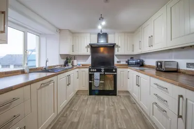 a kitchen with white cabinets and a black stove at Lynwood - 4 Bedroom House with Views of Loch Gilp in Ardrishaig