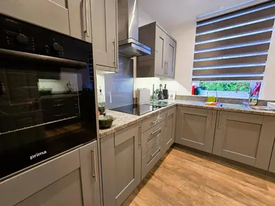 a kitchen with white cabinets and a black appliance at Harbour View - Luxury Town Centre Property in Rothesay