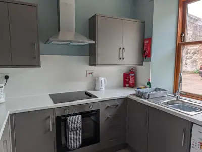 a kitchen with gray cabinets and a sink and a stove at Argyll Place in Campbeltown