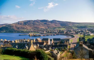 a town on a lake with mountains in the background at Argyll Place in Campbeltown