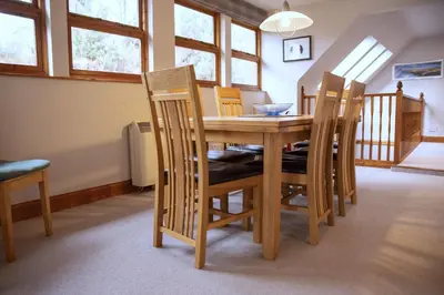 a dining room table with four chairs and a table and chairsktop at Coach House at Morenish Mews in Killin