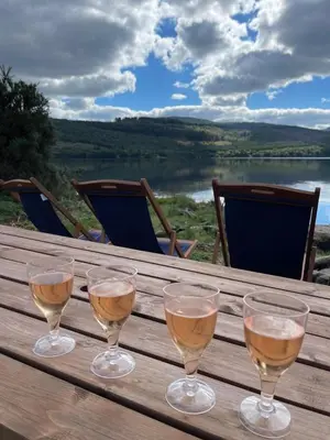 three glasses of wine sitting on a wooden table at Coach House at Morenish Mews in Killin