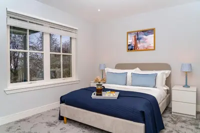 a bedroom with a bed and two windows at Gleneagles Hideaway