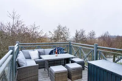 a patio with a couch and a table on a balcony at Gleneagles Hideaway