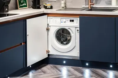 a washing machine in a kitchen with blue cabinets at Gleneagles Hideaway