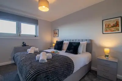 a bedroom with a bed with towels on it at Raeburn House- 3 Bedrooms, 2 Bathrooms in Hamilton in High Blantyre