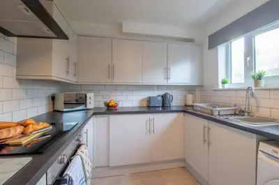 a kitchen with white cabinets and a sink at Raeburn House- 3 Bedrooms, 2 Bathrooms in Hamilton in High Blantyre
