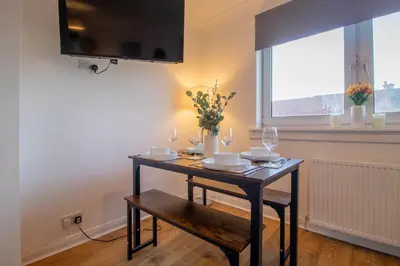 a dining room table with wine glasses and flowers on it at Raeburn House- 3 Bedrooms, 2 Bathrooms in Hamilton in High Blantyre