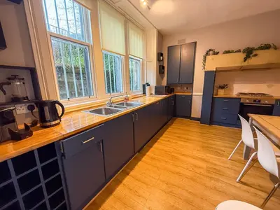 a large kitchen with blue cabinets and wooden floors at Spacious Three Storey West End Home - 3 bedroom in Glasgow