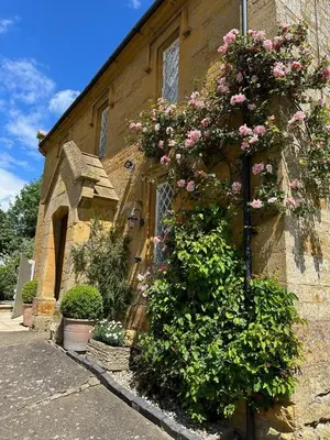 a building with flowers on the side of it at Charming Cotswold stone cottage with garden in Moffat
