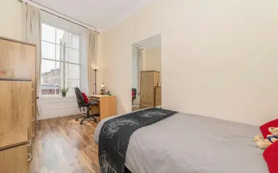 a bedroom with a bed and a desk and a window at 7 Bedroom Apartment - City Centre in Glasgow