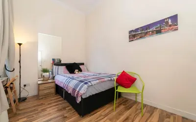 a bedroom with a bed and a yellow chair at 7 Bedroom Apartment - City Centre in Glasgow