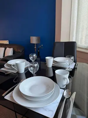 a dining table with white plates and wine glasses at Auldhouse Apartment entire place 2 bedrooms in Mansewood