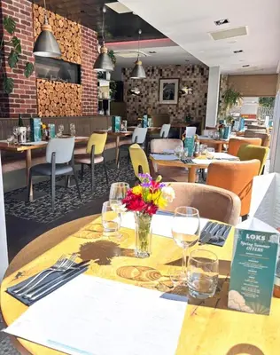 a restaurant with a wooden table with flowers on it at Auldhouse Apartment entire place 2 bedrooms in Mansewood