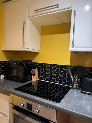 a kitchen with white cabinets and a black counter top at Auldhouse Apartment entire place 2 bedrooms in Mansewood