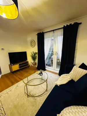 a living room with a table and a tv at Modern 2 Bedroom Ground Floor Apartment near city centre in Glasgow
