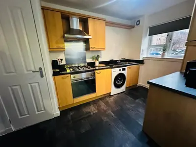 a kitchen with yellow cabinets and a stove top oven at Modern 2 Bedroom Ground Floor Apartment near city centre in Glasgow