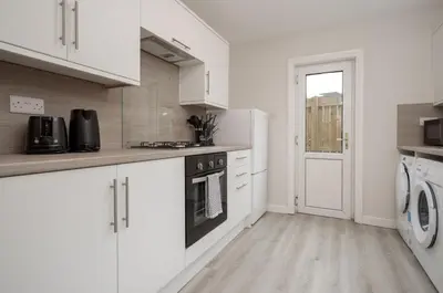 a kitchen with white cabinets and a washer and dryer at 3BR Home Sleeps 6 Near Airport with Parking