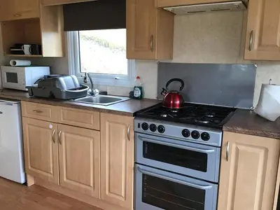 a kitchen with a stove with a tea kettle on it at Cruachan View Caravan Farm stay in Oban