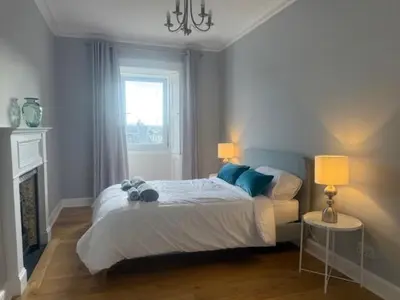 a bedroom with a bed with two lamps and a fireplace at Murrayfield Gem in Edinburgh