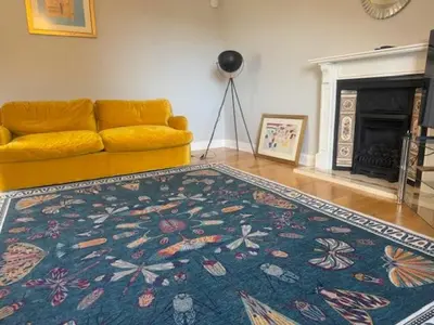 a living room with a yellow couch and a rug at Murrayfield Gem in Edinburgh