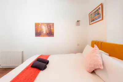 a white bed with a red and black towel on it at Central Cosy Apartment by Meadows 6 in Edinburgh