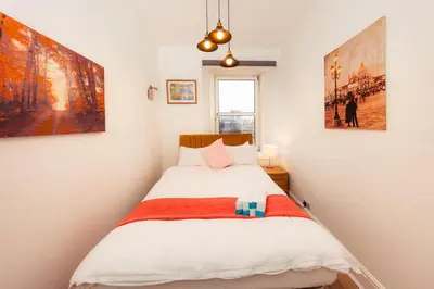 a small bedroom with a bed and paintings on the wall at Central Cosy Apartment by Meadows 6 in Edinburgh