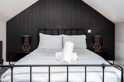 a black and white bedroom with a bed and two lamps at No8 Peebles Retreat - Donnini Apartments in Ayr