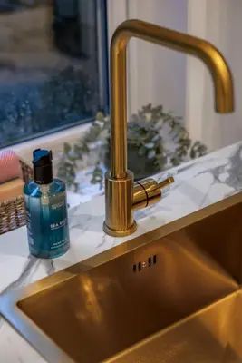 a sink with a bottle of soap sitting next to it at Cosy Callander One Bed Apartment Wood Burner and Free Parking in Callander