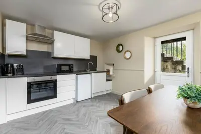 a kitchen with a wooden table and white cabinets at The Bruces Quarter in Stirling