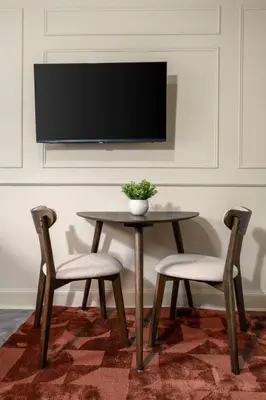 a table with two chairs and a tv on a wall at Caledonia Suite by The Wallace Monument in Stirling