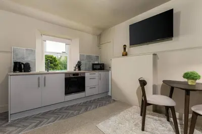 a kitchen with a table and a tv on the wall at The Wallace Suite by The Wallace Monument in Stirling