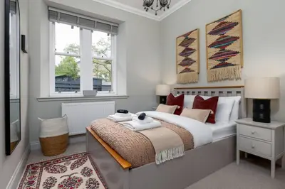 a bedroom with a large bed and two windows at Kings Park Garden Cottage - Free Parking in Stirling