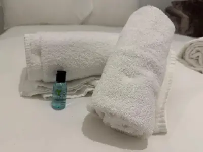 a pile of towels and a bottle of soap on a bed at West End Stay by Kelvingrove in Glasgow