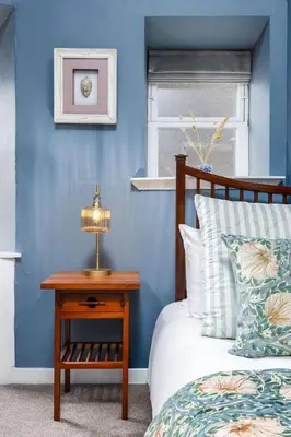 a blue bedroom with a bed and a table with a lamp at Elegant 3 Bed Apartment in Stirling Near Free Parking and Hill Views in Stirling